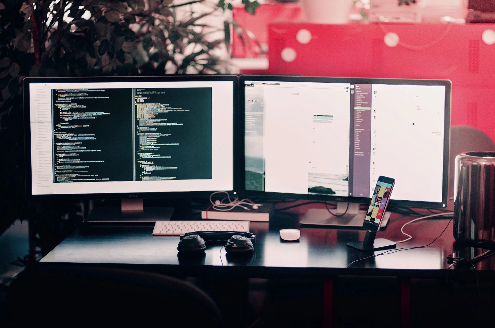 A programmer's desk with a laptop, coding on the screen, notebooks, and a cup of coffee in a modern workspace.