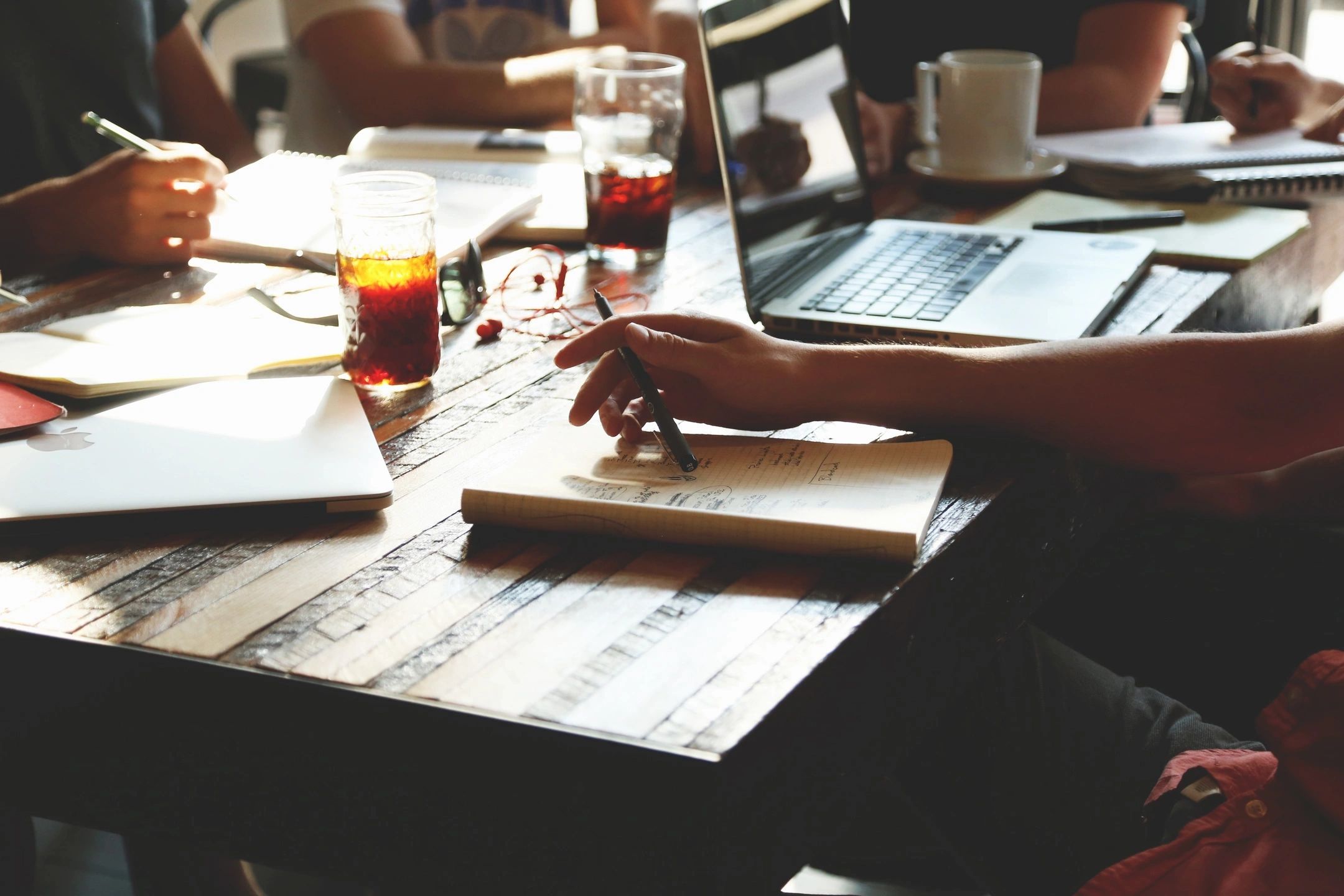 A laptop and a pair of glasses on a neat desk, surrounded by project management books